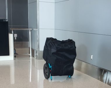 An electric wheelchair sits covered at an airport gate. 
