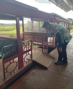 A worker at the Dole Plantation in Oahu, Hawaii, places a ramp to allow wheelchair access to a tourist train car.