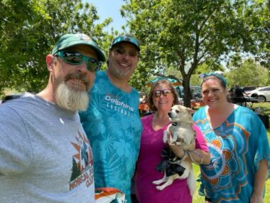 Two couples pose for a photo in the park at a Miami Dolphins fan club barbecue.