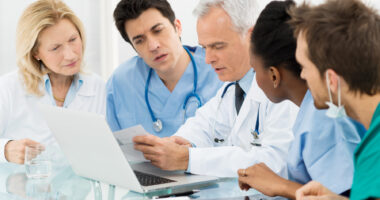 A group of medical professionals gathered around a chart and discussing.