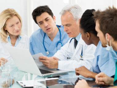 A group of medical professionals gathered around a chart and discussing.