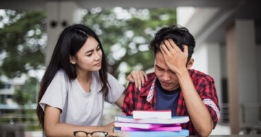 A woman comforts a man with his head in his hands