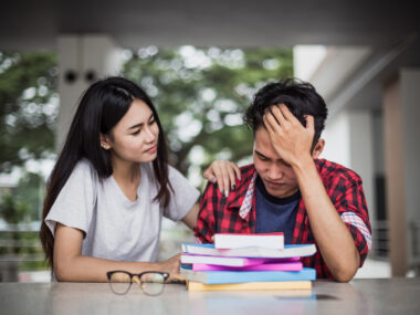 A woman comforts a man with his head in his hands