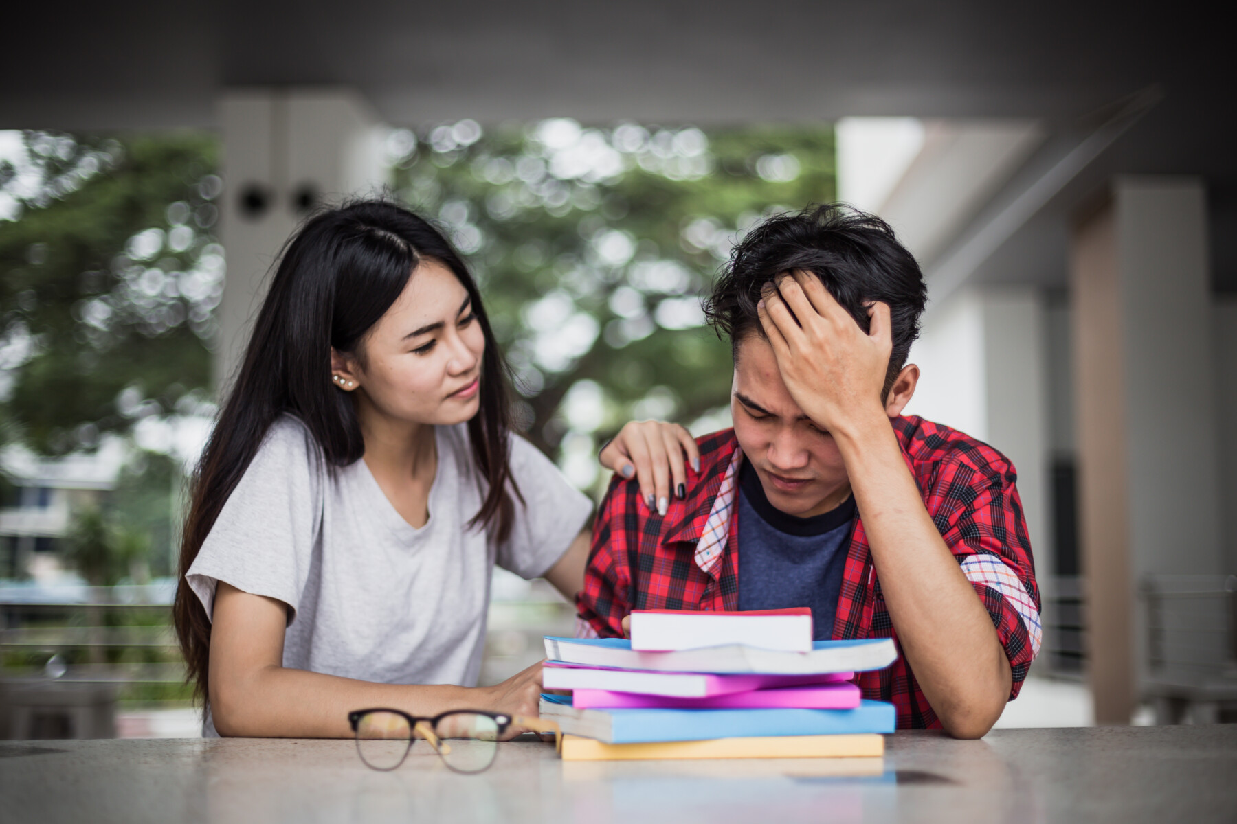 A woman comforts a man with his head in his hands