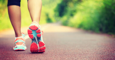 A female walking shown from the calf down on a paved road