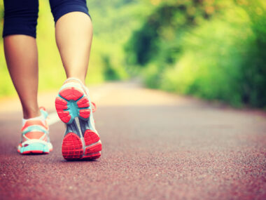 A female walking shown from the calf down on a paved road