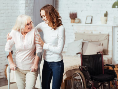 an occupational therapist helping a woman in her home with a wheelchair beside them